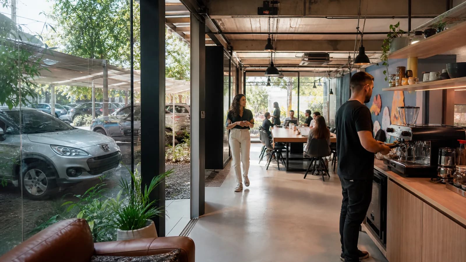 Estação de café em coworking com máquina de espresso e estacionamento visível pela janela